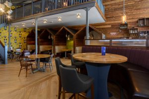 Interior of the bar and dining area at Grange Leisure Park near Mablethorpe, Lincolnshire, featuring bespoke wooden booths, modern furnishings, and a mezzanine level, designed by Norfolk architects Paul Robinson Partnership