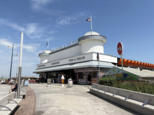 External view of Britannia Pier, blue skies, white render dome towers, flags, raised letter sign, zinc, seaside