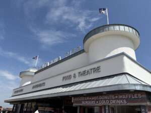 External view of Britannia Pier, blue skies, white render dome towers, flags, raised letter sign, zinc, seaside
